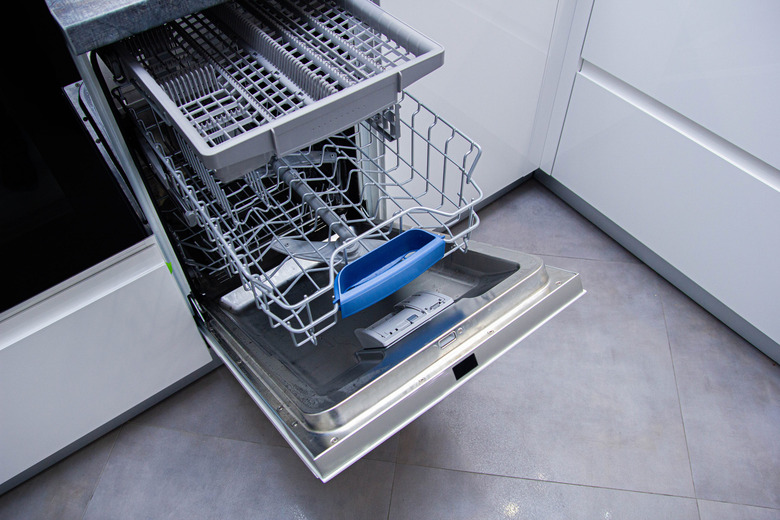 open modern dishwasher in the kitchen; built-in appliances in furniture.