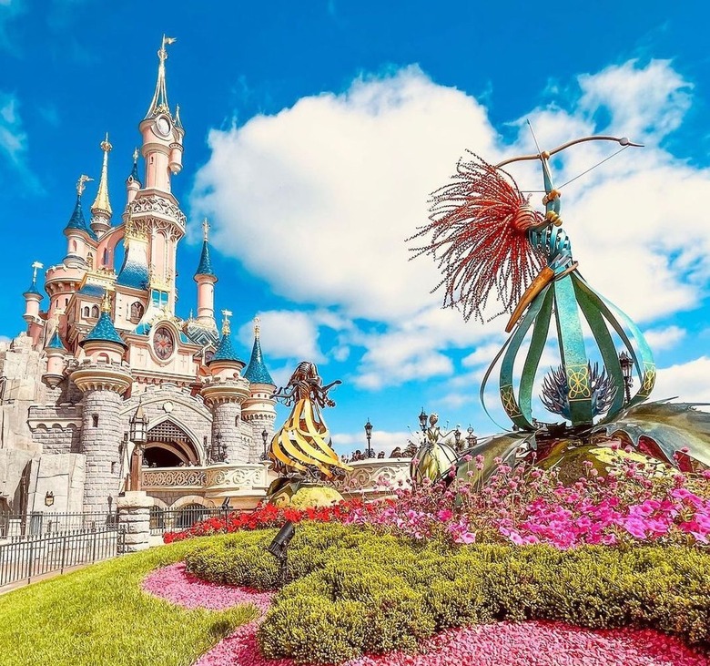 Image of Disneyland Paris castle with a blue sky and greenery in the front.