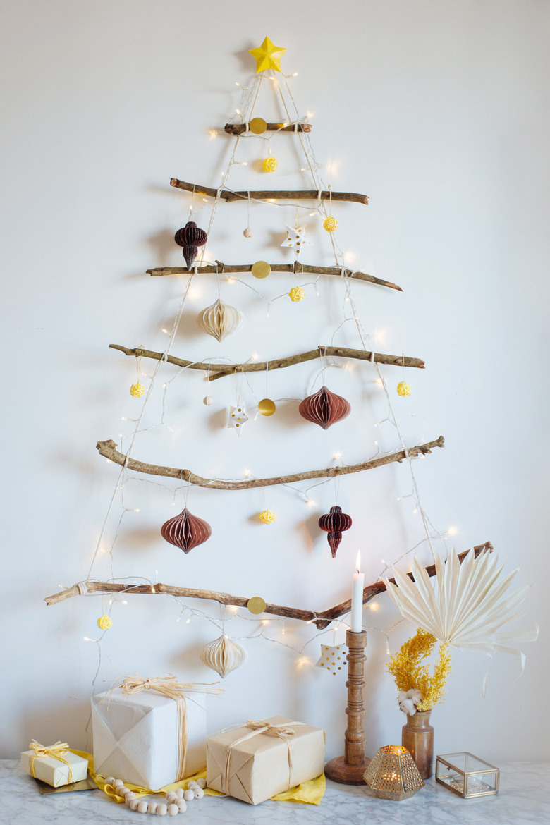 branch and twinkly light DIY Christmas tree hung on the wall