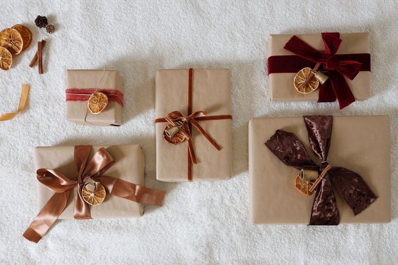 Dried orange gift toppers tied to five gifts wrapped with brown Kraft paper and velvet ribbon