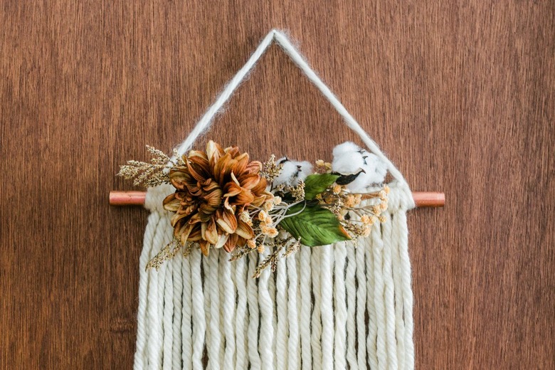 DIY fall decor idea with white yarn wall hanging with faux flowers and copper pipe