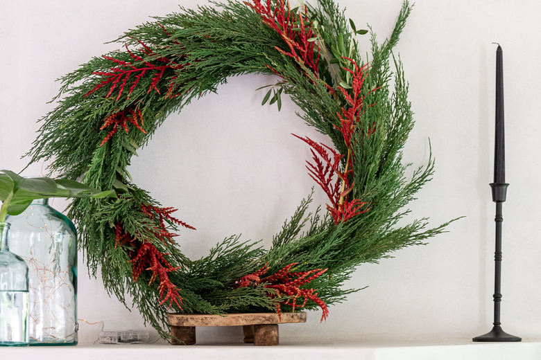 Faux holiday wreath with cedar on mantel.