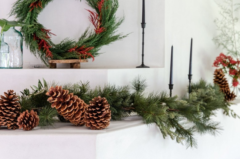 christmas garland on mantel with black taper candlesticks and fresh flowers