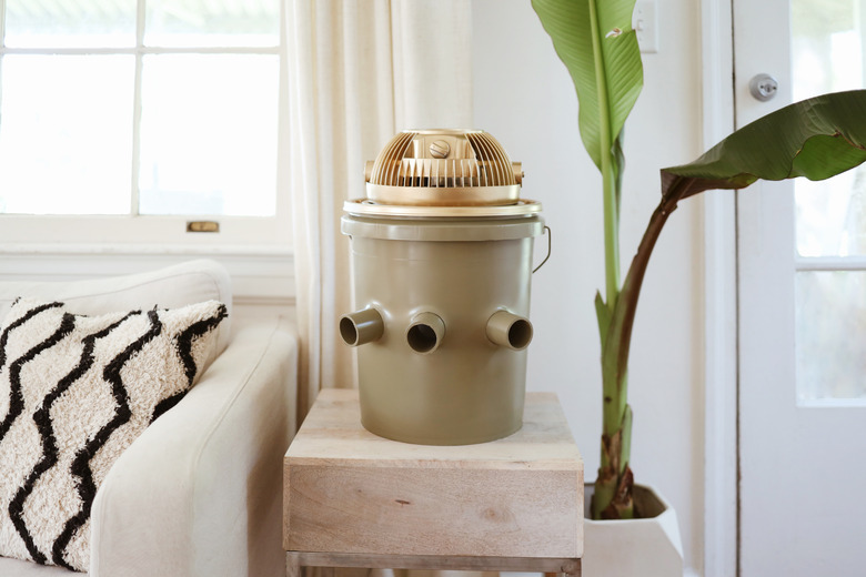 Green and gold portable bucket air conditioner on an end table next to a couch