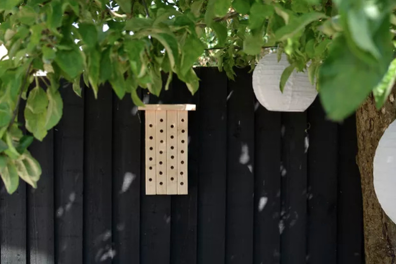 Modern wood bee house against black fence