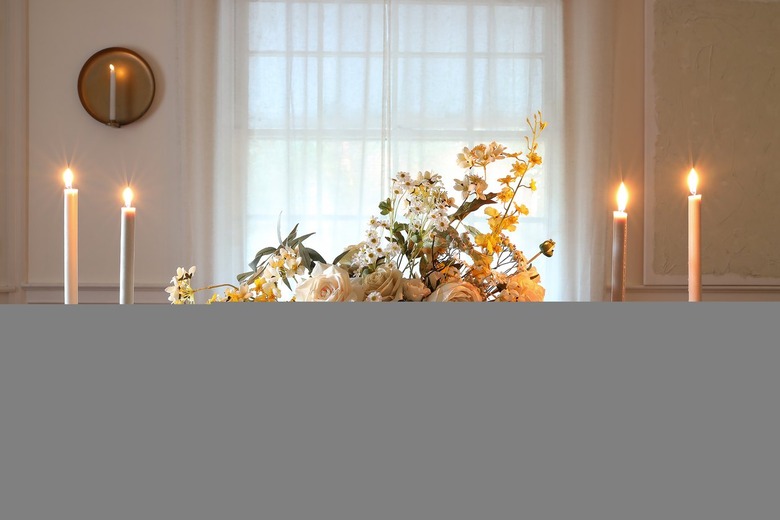 DIY white and yellow spring floral centerpiece on table with candles