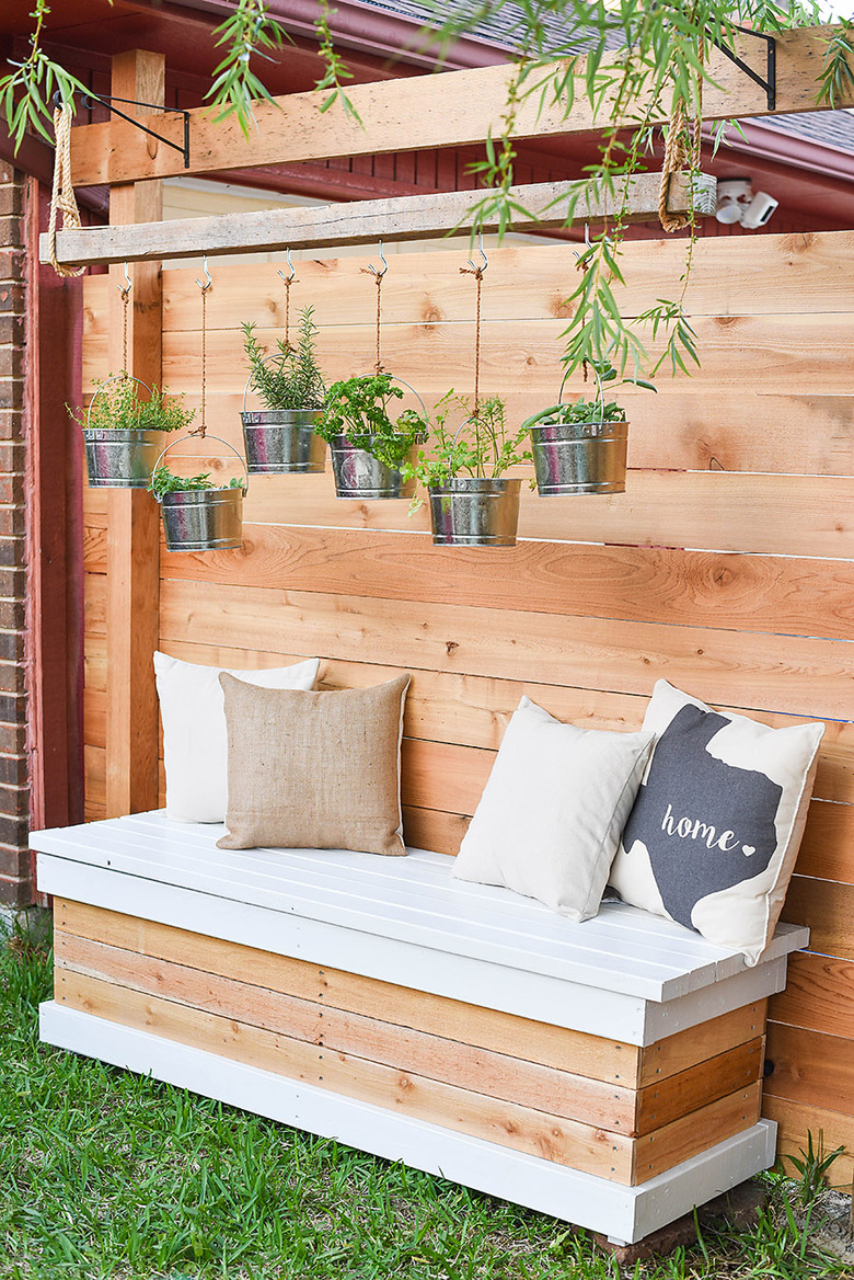 DIY storage bench for backyard in white and a wood finish with throw pillows