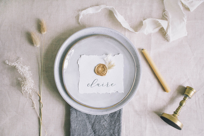 DIY gold wax seal place card with dried florals on top of place setting on table