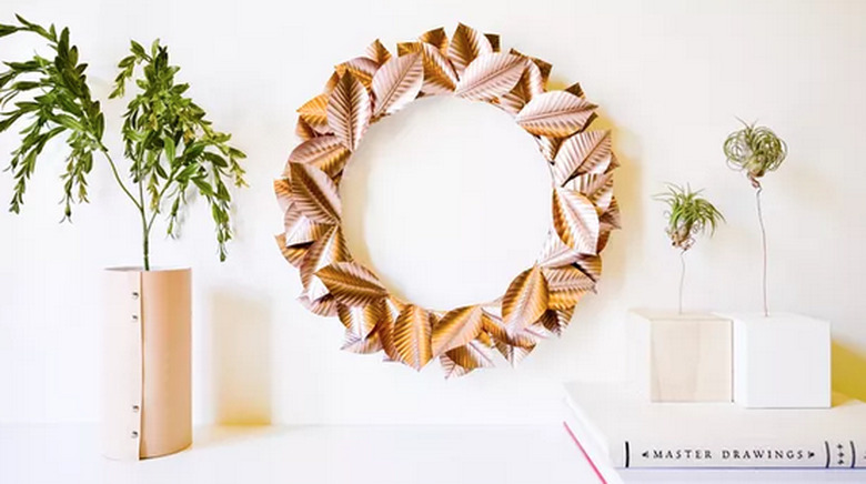 Rose gold wreath next to leather-wrapped vase with greenery