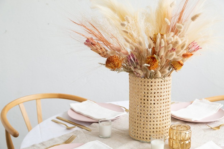 Vase wrapped in cane with dried flowers and grass on dining table