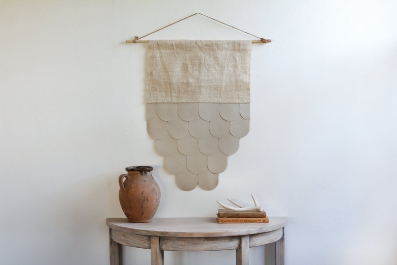 Leather-burlap wall hanging over half-moon table with decorative vase