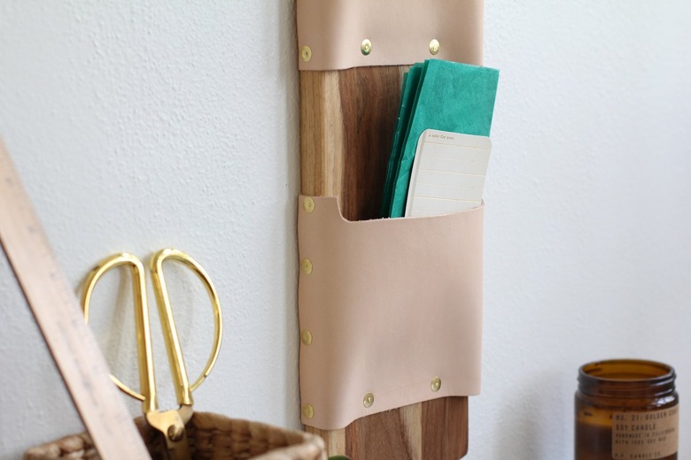 a wall-mounted letter holder made from a cutting board and leather strips