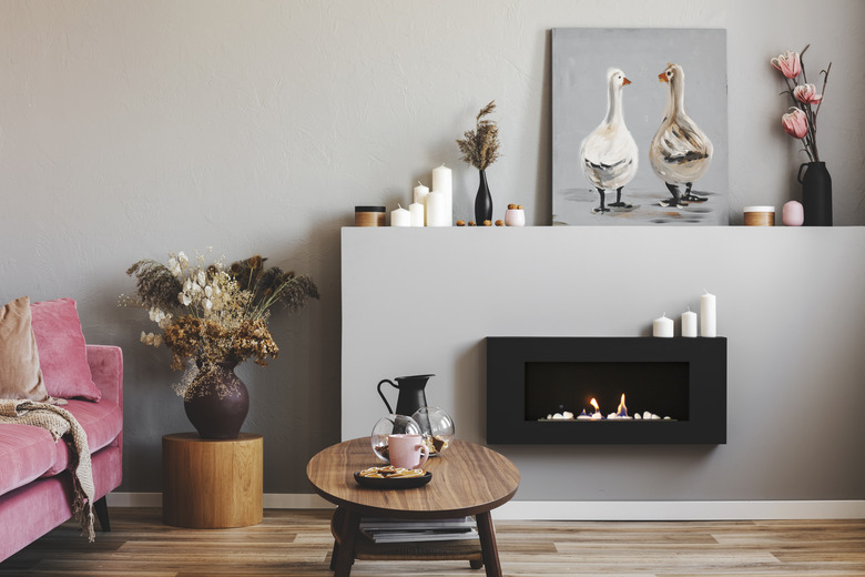 Elegant living room interior with black and grey fireplace, wooden coffee table and pink couch