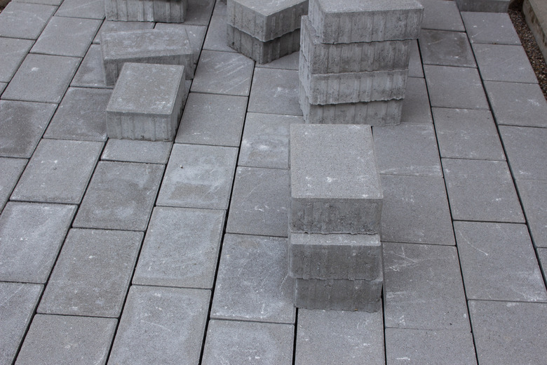 Concrete paver blocks laid beside a building, some paving stones are stacked for future use