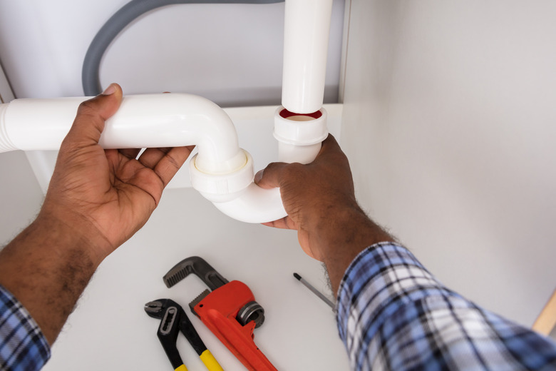 Plumber Fitting Sink Pipe In Kitchen