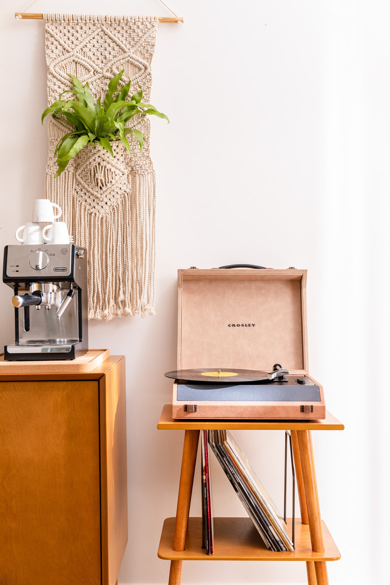 Record player on wood table and macrame plant hanger