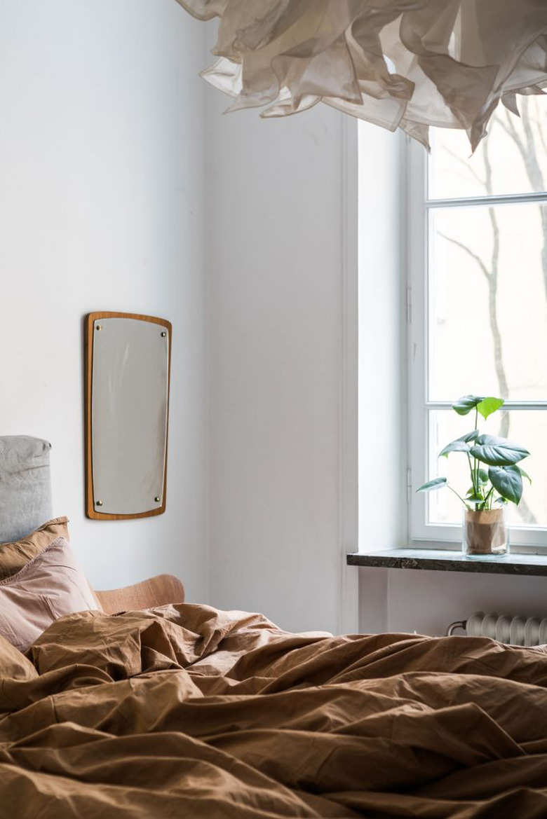 rumpled rust-orange hued  linen sheets in moody bedroom