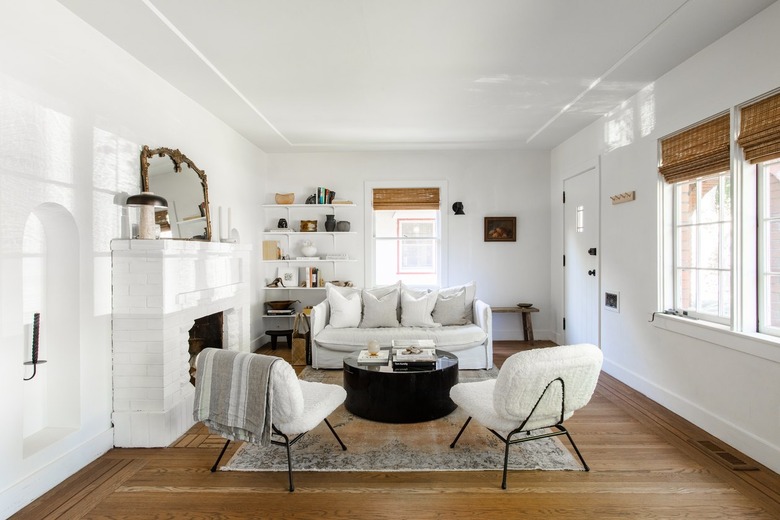 A white living room with multiple windows, a fireplace, and white, modern furniture