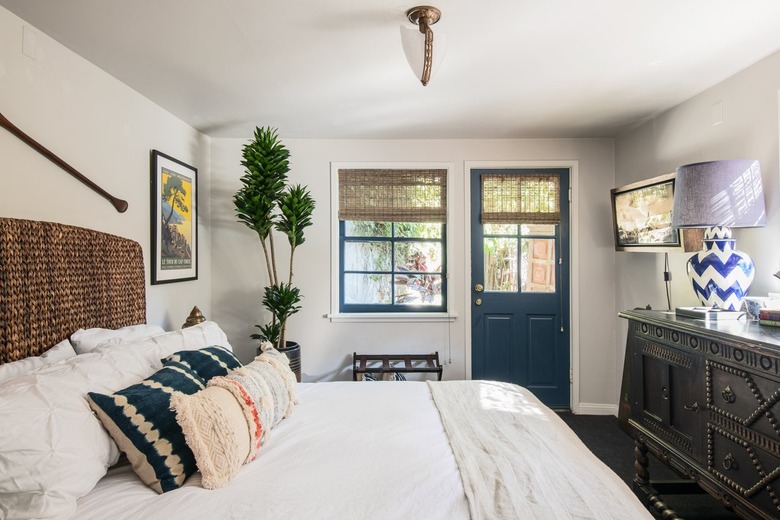 Neutral roller shades are hung over a window and a door in a bedroom