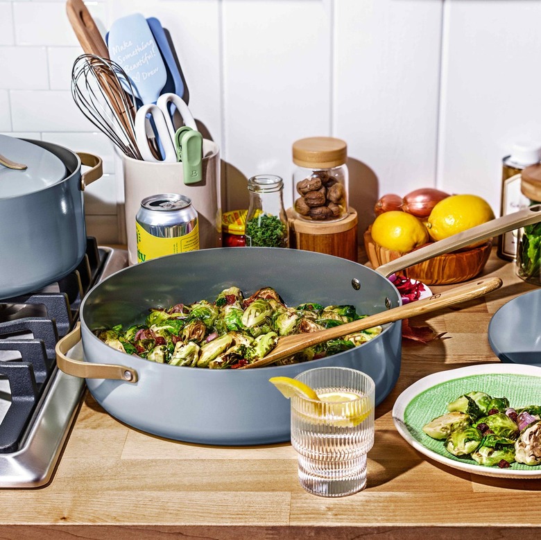 A dusty blue skillet full of brussel sprouts on a wooden countertop.