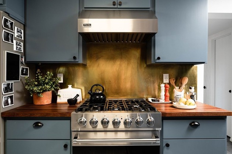 Kitchen with stainless stove, hood, blue cabinets.