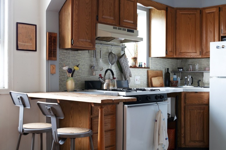 Kitchen with wood cabinets, bar, white stove, white refrigerator.