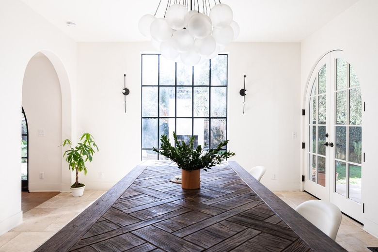 A wood table in a white-walled dining room with arch doorways