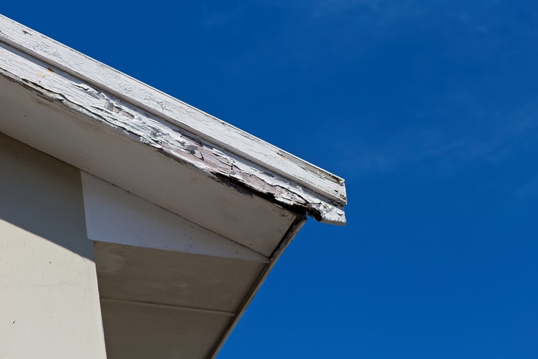 Roof repair and maintenance concept image consisting of old rotting fascia boards and a blue sky background.