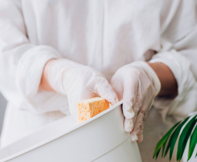 Cleaning white garbage can with sponge