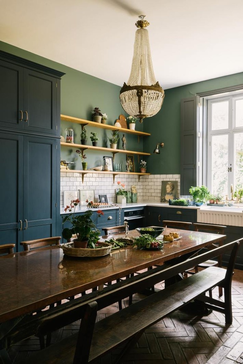 green and white eat-in kitchen with antique chandelier and vintage wood table