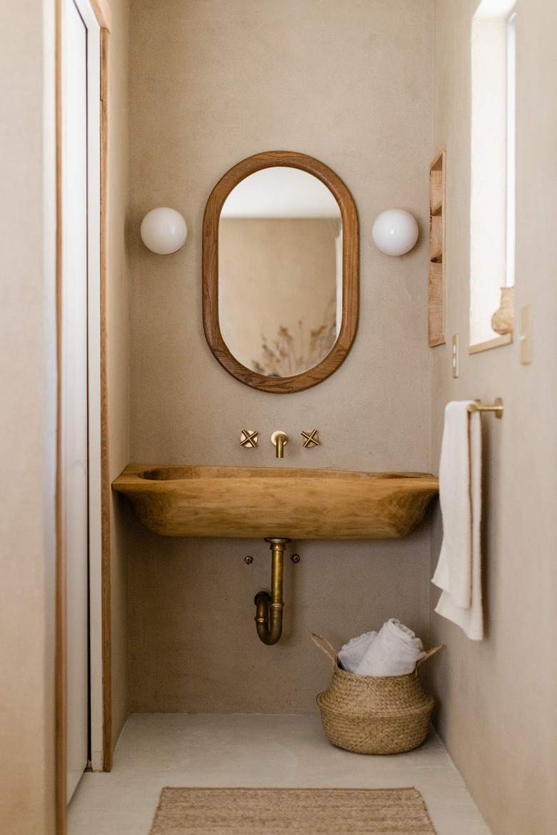 eco-friendly bathroom with concrete sink and oval mirror above it