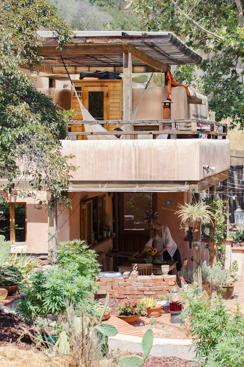 a two-story home with various levels of landscaping, hanging pots and hardscapes