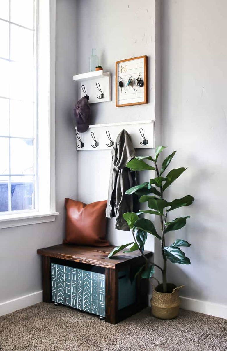 Fabric mud cloth entryway shoe storage bin under small wood bench in entryway