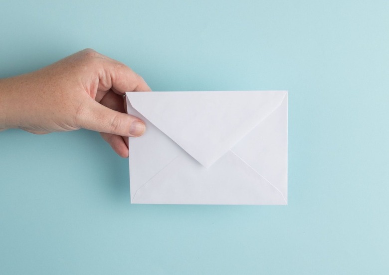 person holding envelope over light blue background