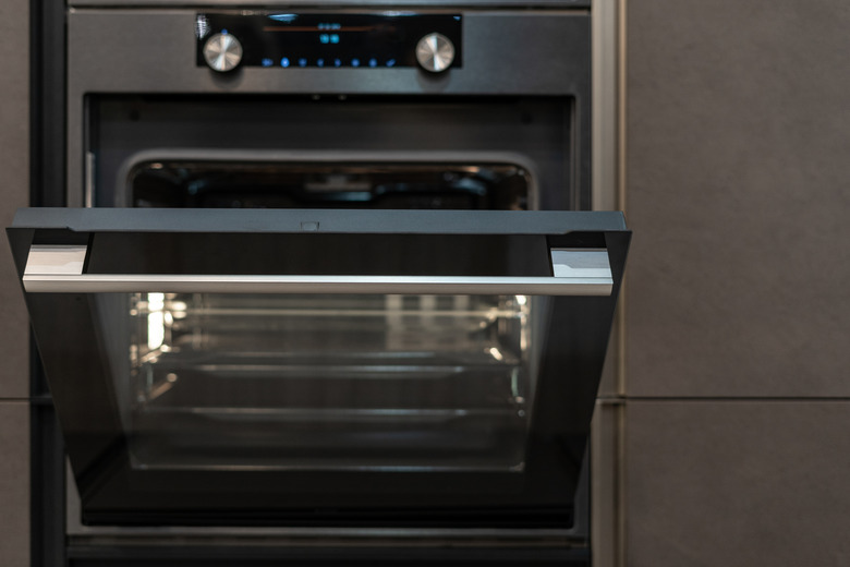 Front view photo of open door on  modern oven built-in in black kitchen cabinet