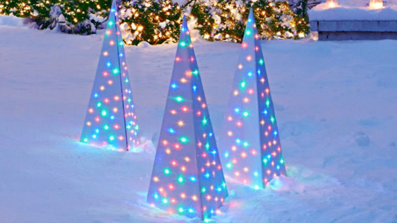 exterior Christmas decorations with Multi colored lights inside modern Christmas trees outside on patch of snow.