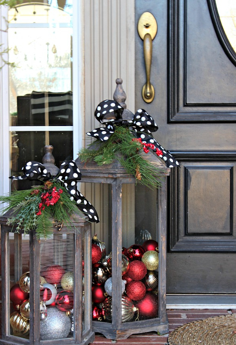 exterior Christmas decorations with Distressed lanterns filled with holiday ornaments, greenery, polkadot ribbons, black front door.