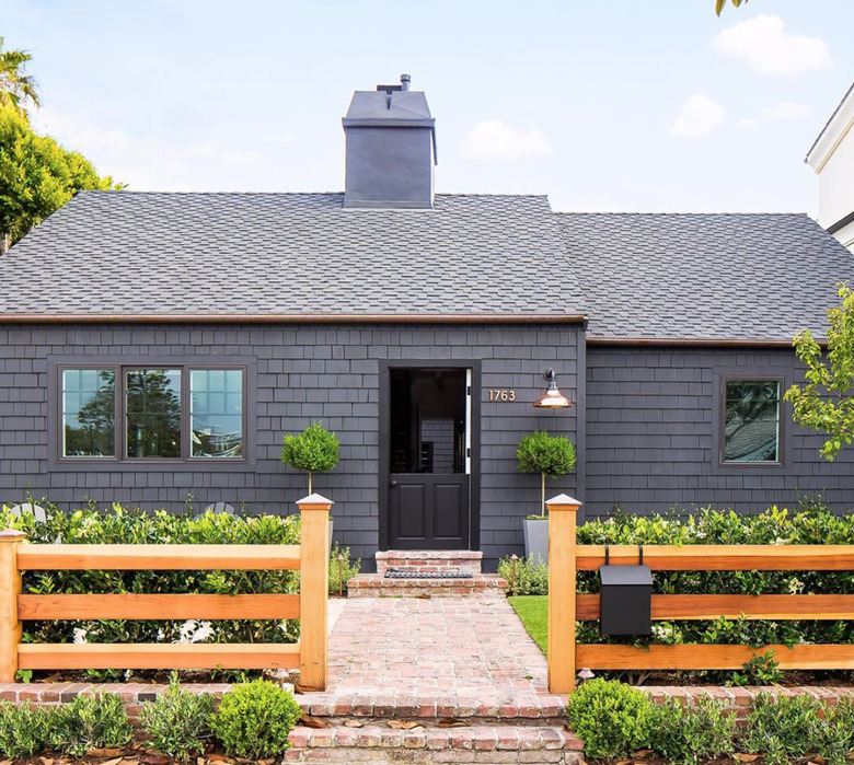 gray house with black exterior Dutch door and wood fence