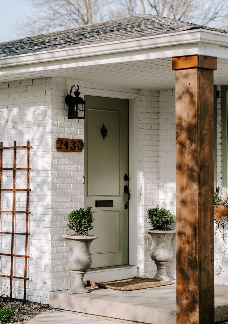 Lantern-style exterior house light on white brick exterior next to front door