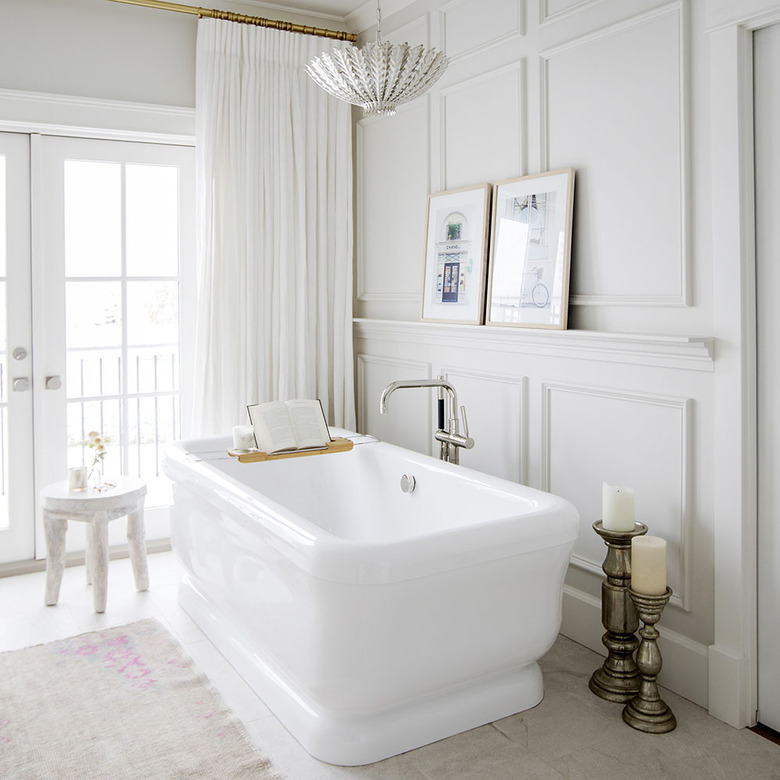 all white bathroom with freestanding tub and floor-to-ceiling drapery