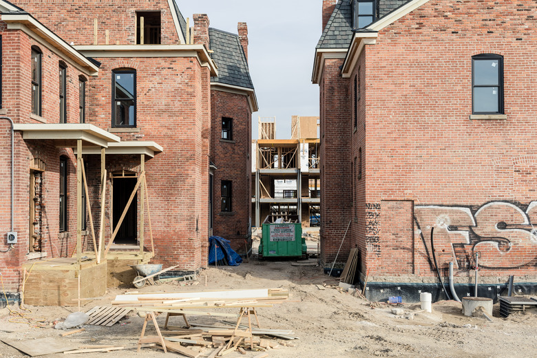 unfinished construction project on red brick home surrounded by dirt and wood