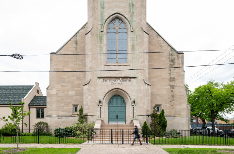 exterior of church with black gate and person walking past