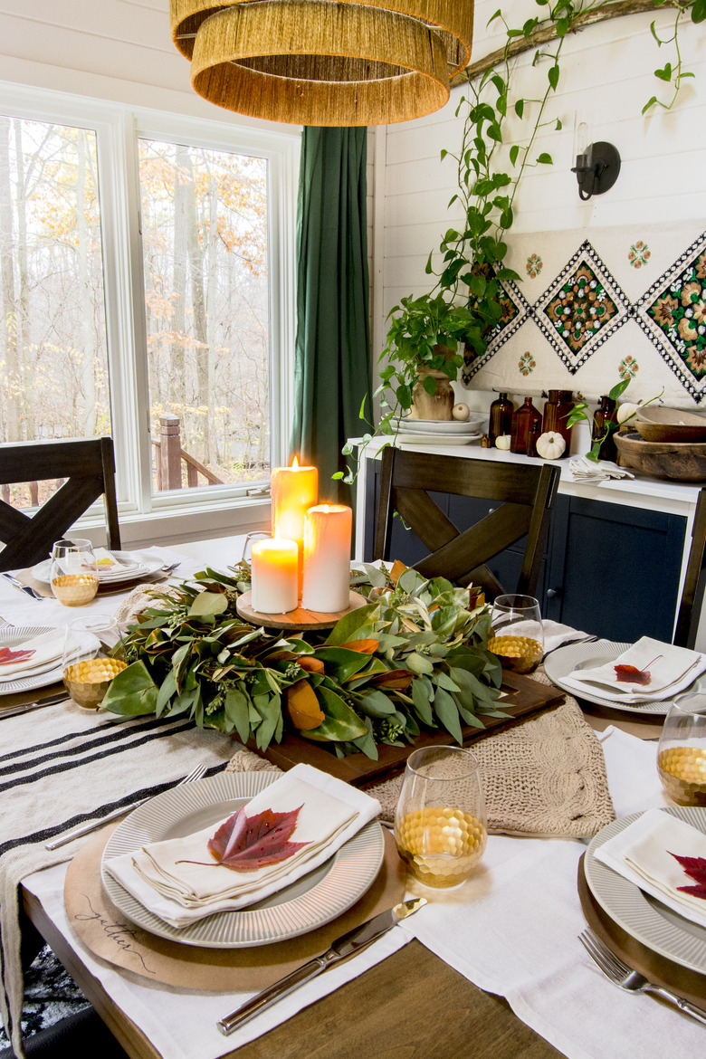 Fall centerpiece with green leaves and candles in bohemian dining room