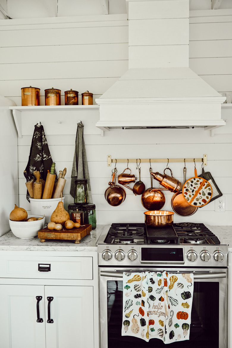 fall kitchen decor in white kitchen with copper pots hanging above the stove