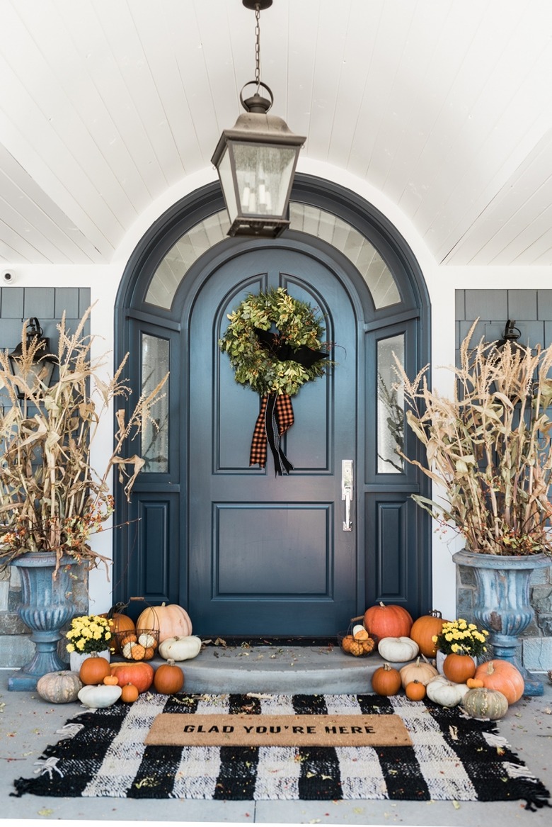 fall porch decor with black front door and checkered mat