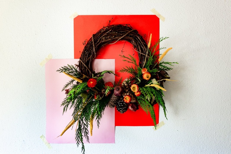 fall wreath made with cedar branches, pine cones, dried flowers, and dried pomegranates