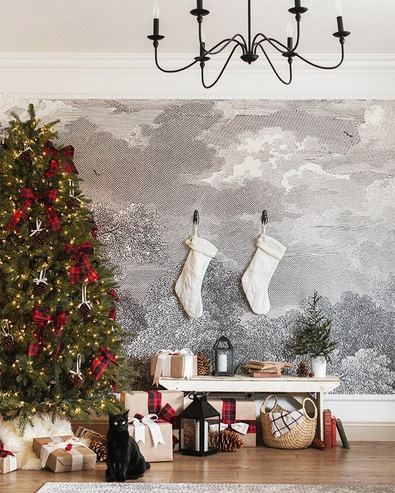 farmhouse Christmas tree idea with red bows in front of wall mural