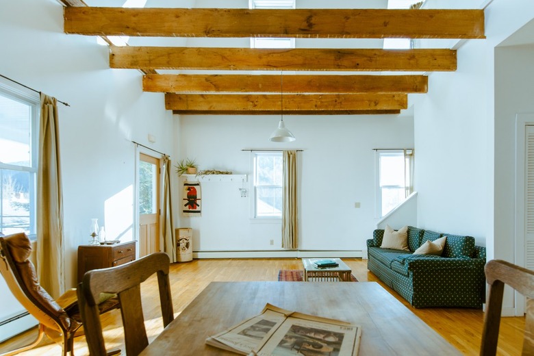 Minimalist living room with wood beam ceiling, skylights and white walls