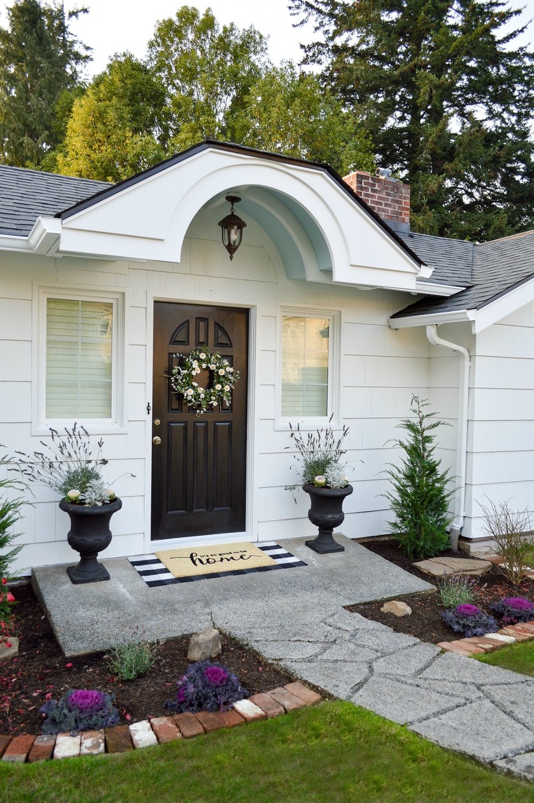 white farmhouse exterior with lantern light fixture and brown door