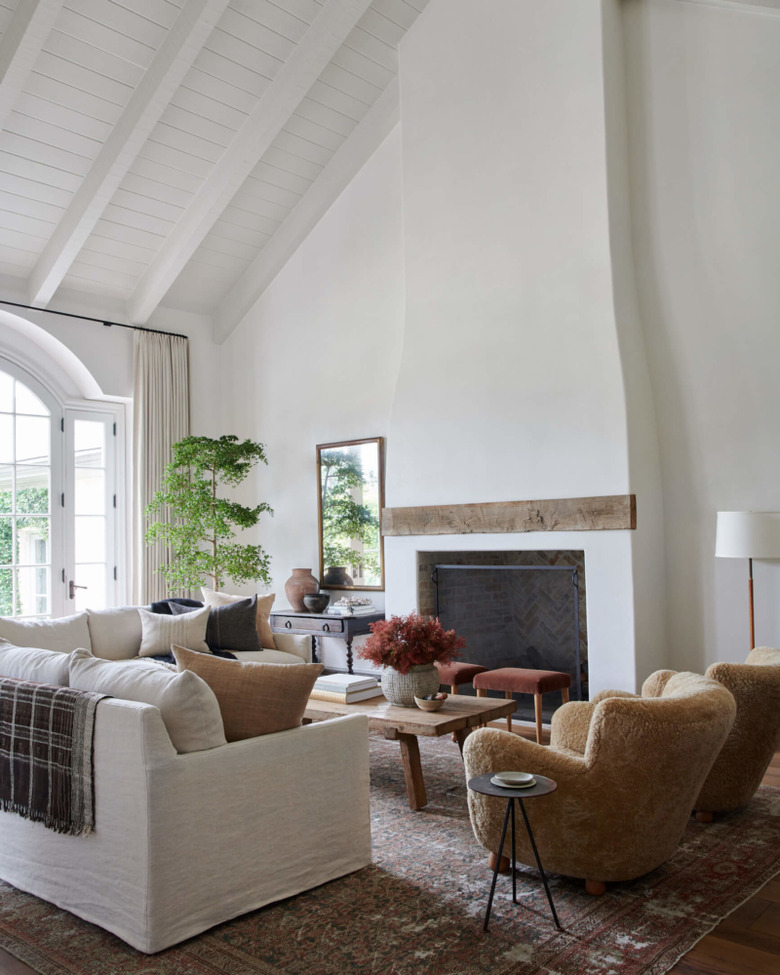 Living room with couch, chairs, coffee table, large farmhouse fireplace, vintage rug.